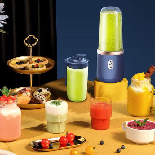 Portable blender with green juice on a table with desserts and drinks